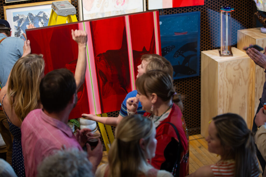A child holding a painting depicting a shark as an adult helps them.
