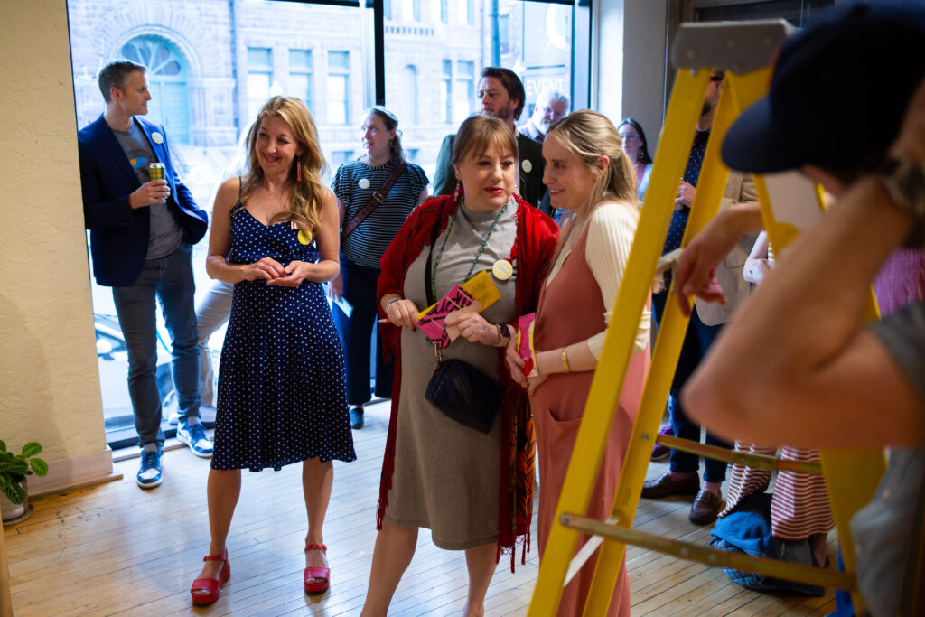 Two people talking and standing next to each other, while others look on.