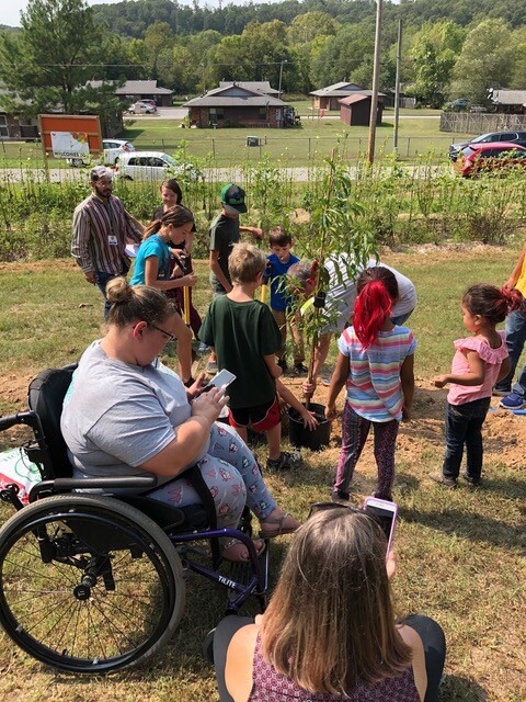 Adults and children work together to plant a tree as part of Welcoming America's Welcoming Week.