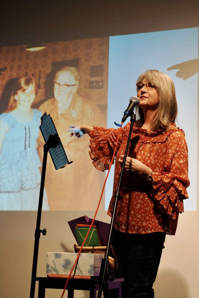 A woman points to a projection of her and her grandmother