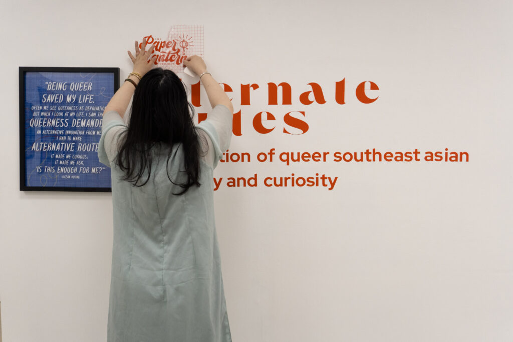 A person with long black hair wearing a traditional Vietnamese ao dai hanging gallery signage.