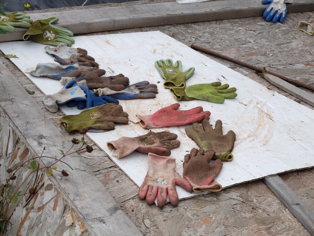 Various dirty gardening gloves scattered on wood.