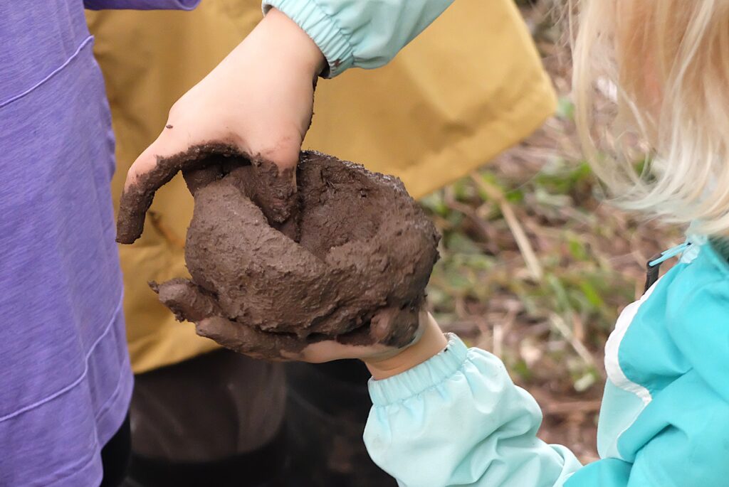 A set of children's light skin tone hands forming brown clay.