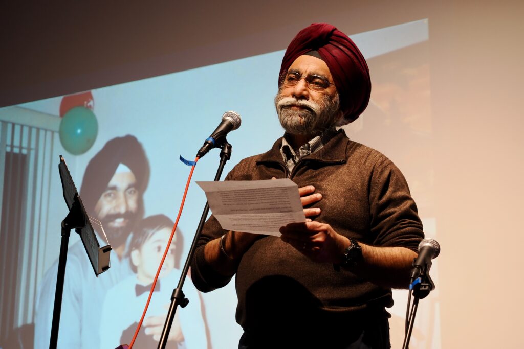 A man in a turban reads a letter and holds his hand to his heart