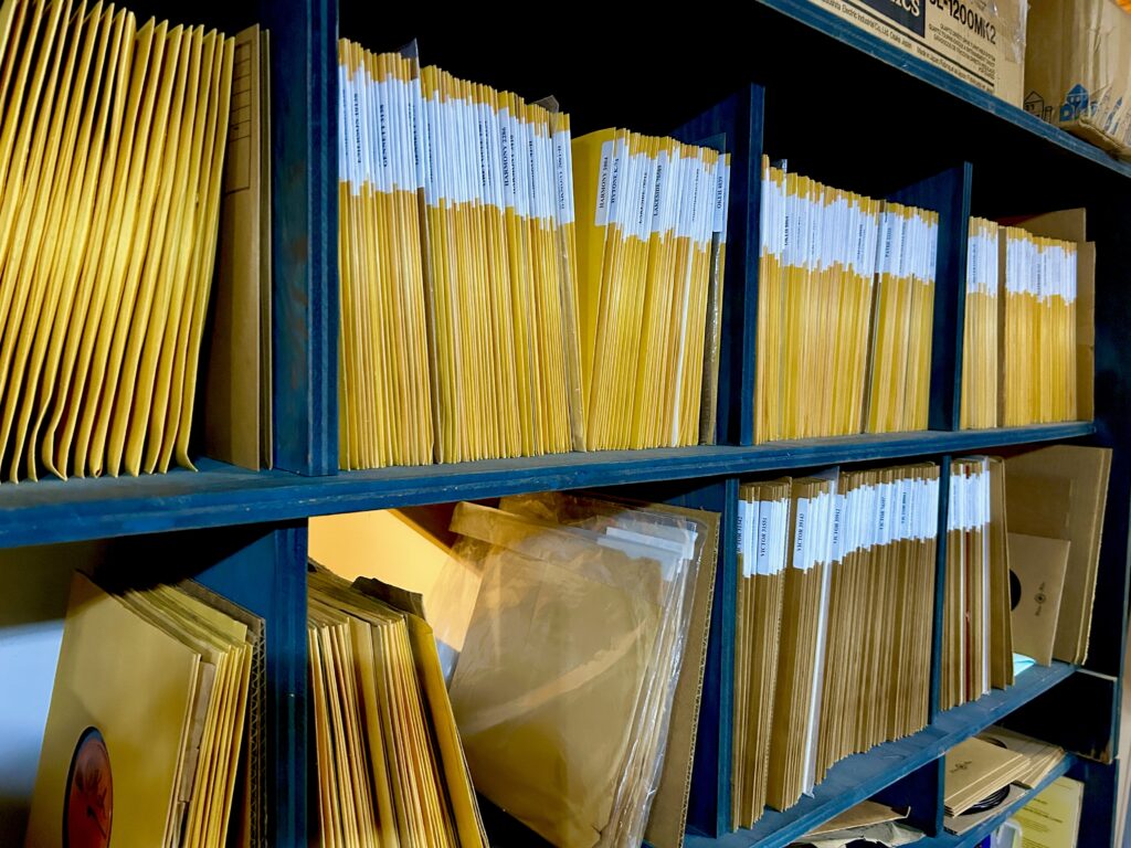 Shelves full of yellow square envelopes containing music recordings on vinyl.