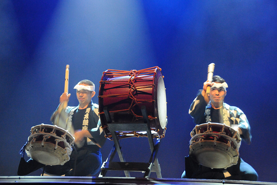 Ondekoza, a band based in Japan who masters in taiko drumming, perform on a stage cast in blue light.