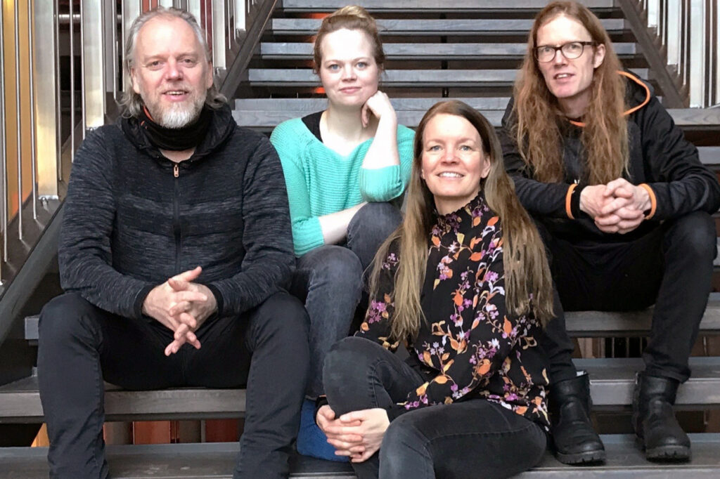 Unni Boksasp, a Norwegian folk singer, poses with her ensemble sitting on a set of stairs.