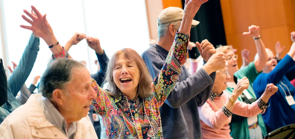 A group of people smile and raise their arms in a room together.