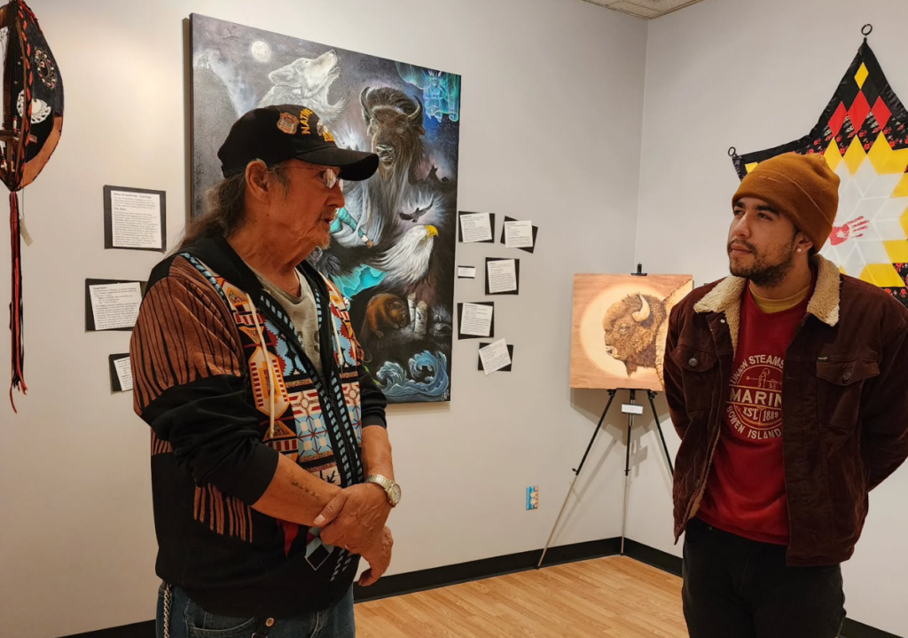 Two people talk to each other inside an art gallery